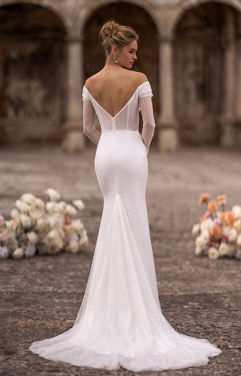 Woman in a white wedding dress standing in an outdoor setting with floral arrangements.
