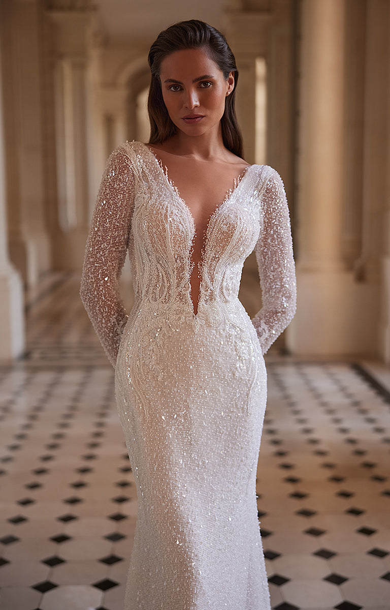 Woman wearing a white beaded wedding dress in an elegant indoor setting.
