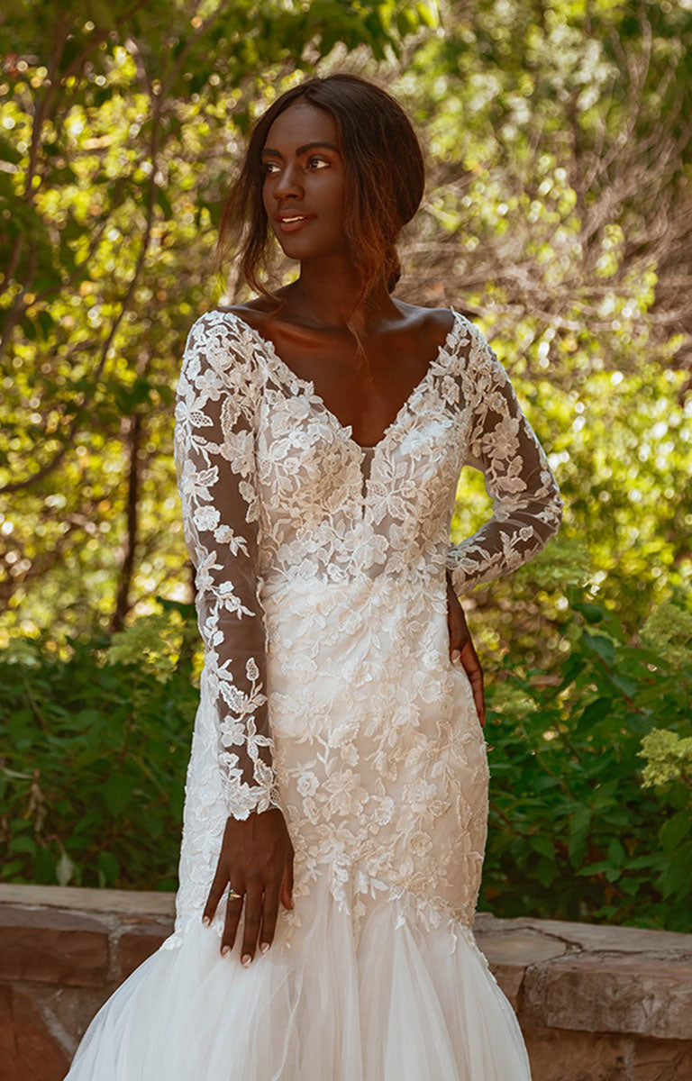 Woman wearing Style 7491 by Essense of Australia - Long Sleeve Lace Fit-and-Flare Wedding Dress with Train with long sleeves in a forest setting