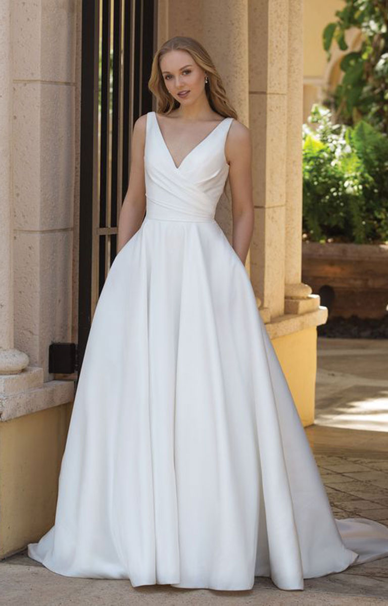 Woman wearing 44080 by Sincerity Bridal - Asymmetric Mikado Ball Gown with Draped Neckline and Pockets standing in front of classical architecture.