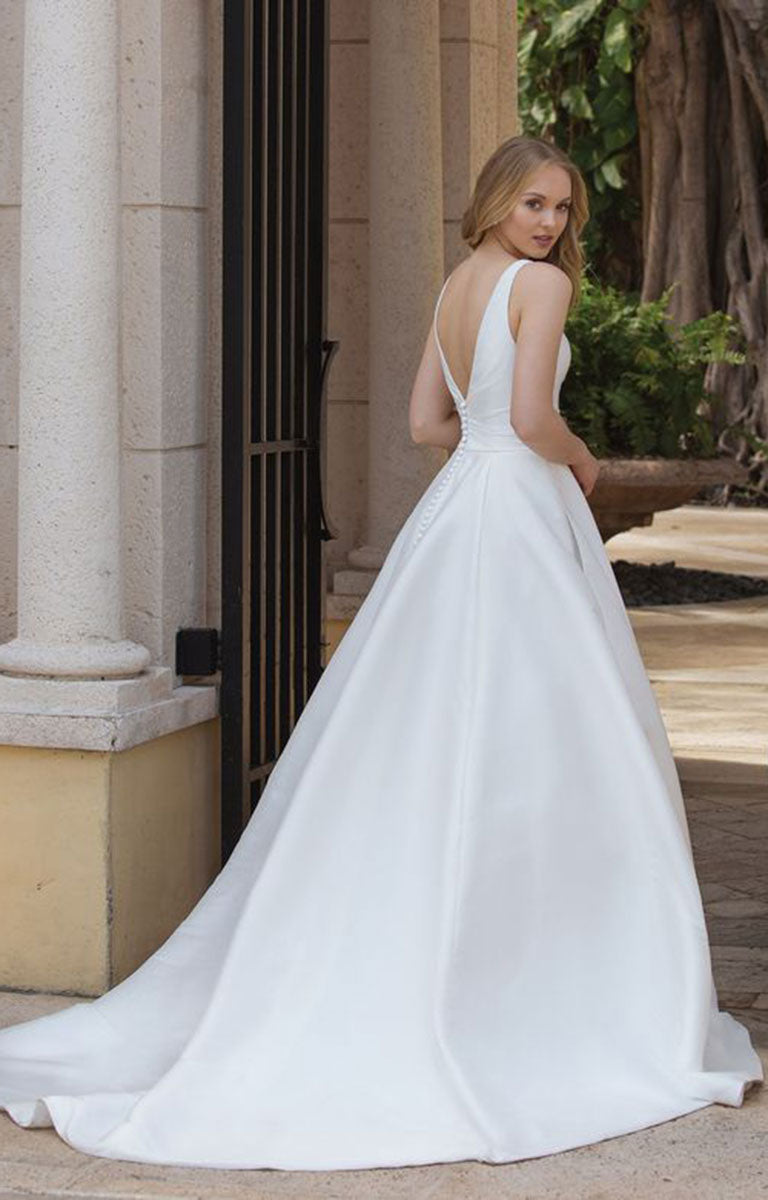 Woman in 44080 by Sincerity Bridal - Asymmetric Mikado Ball Gown with Draped Neckline and Pockets standing outdoors near classical architecture.