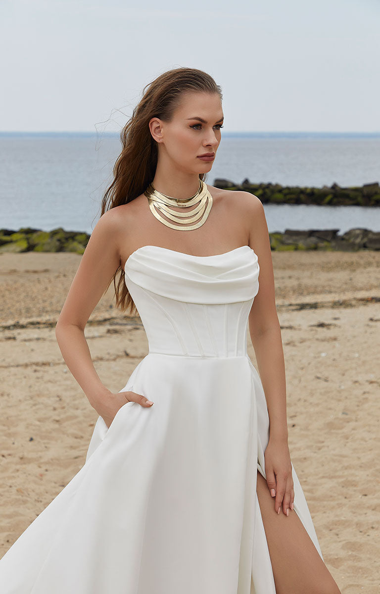 Woman in a white strapless dress on a beach with ocean in the background
