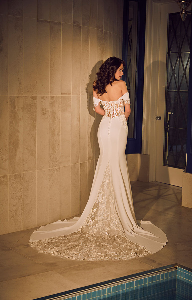 Woman in a white lace wedding dress standing by a pool.