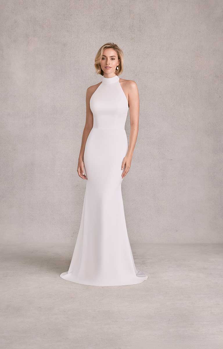 Woman wearing a white halter neck gown against a plain background