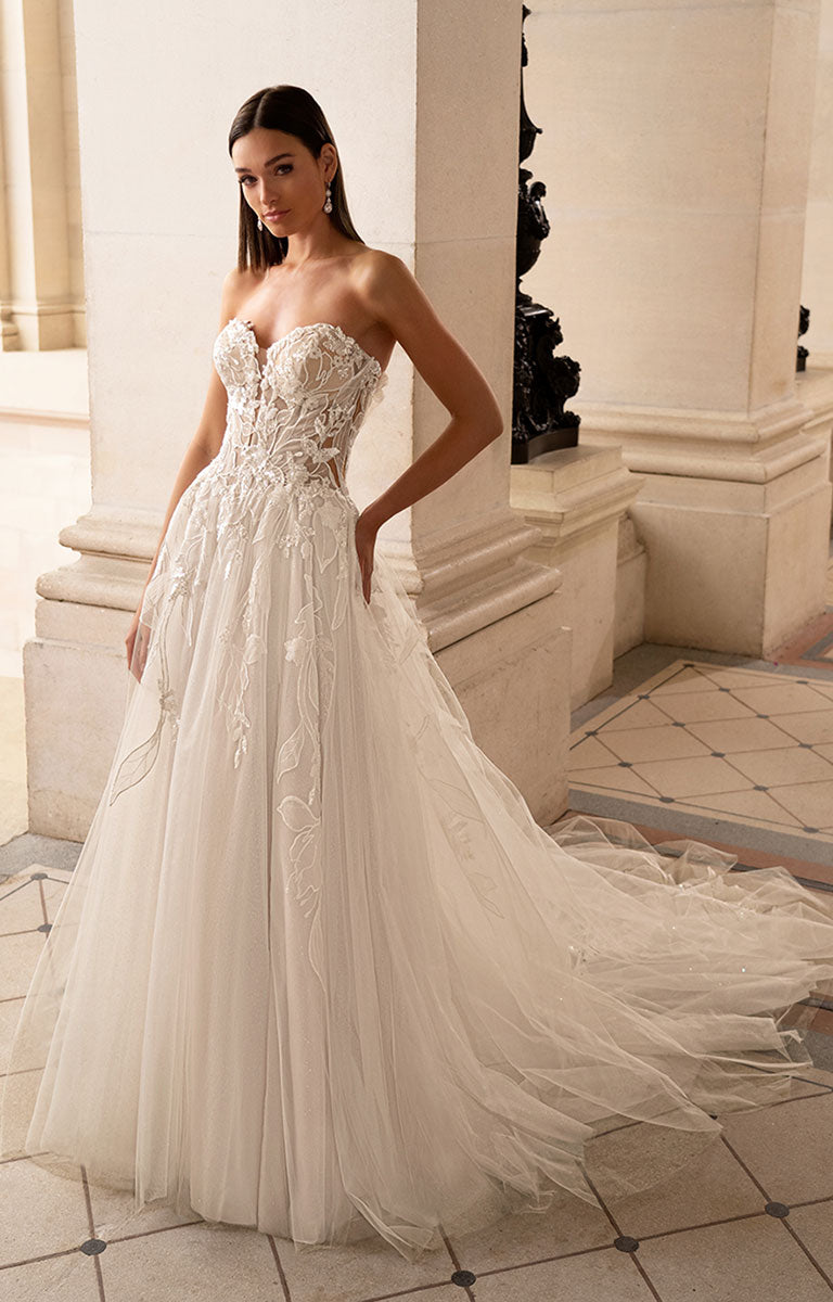 Woman wearing a strapless lace wedding dress in an elegant indoor setting.