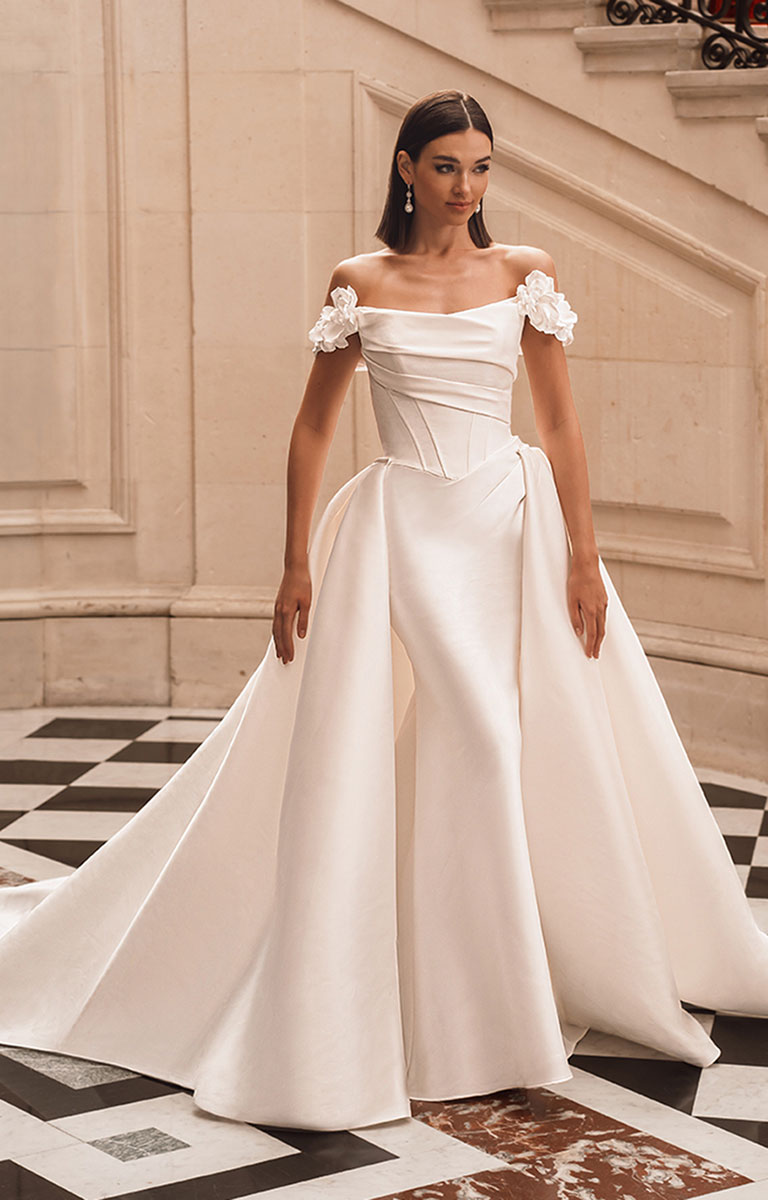 Woman in a white wedding dress standing in an elegant interior setting.