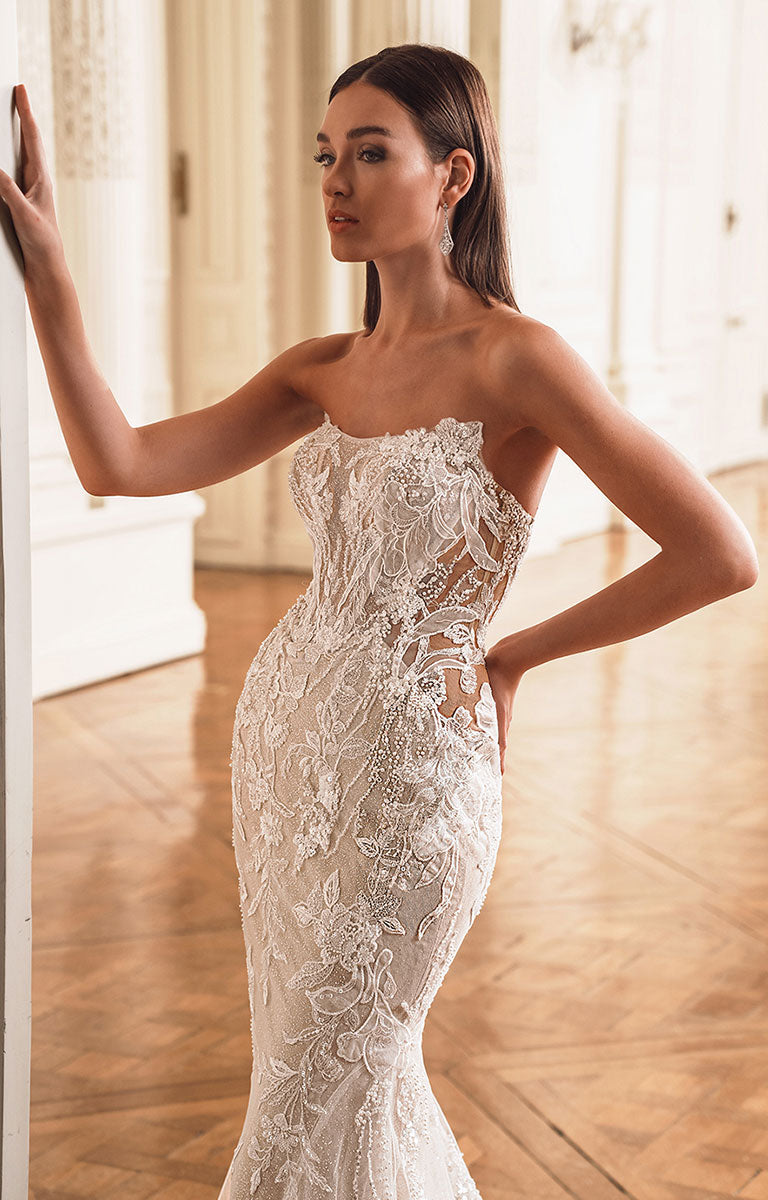 Woman wearing a white lace wedding dress in a softly lit room.