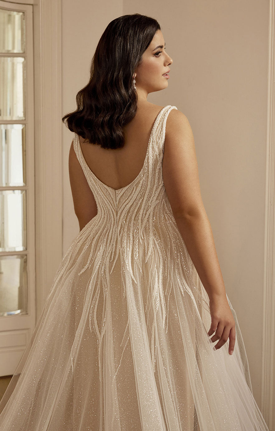 Woman wearing a beige evening gown with a backless design in an indoor setting.