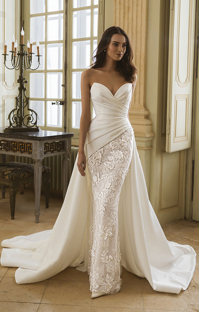 Woman in a strapless wedding gown with floral details in an elegant room.