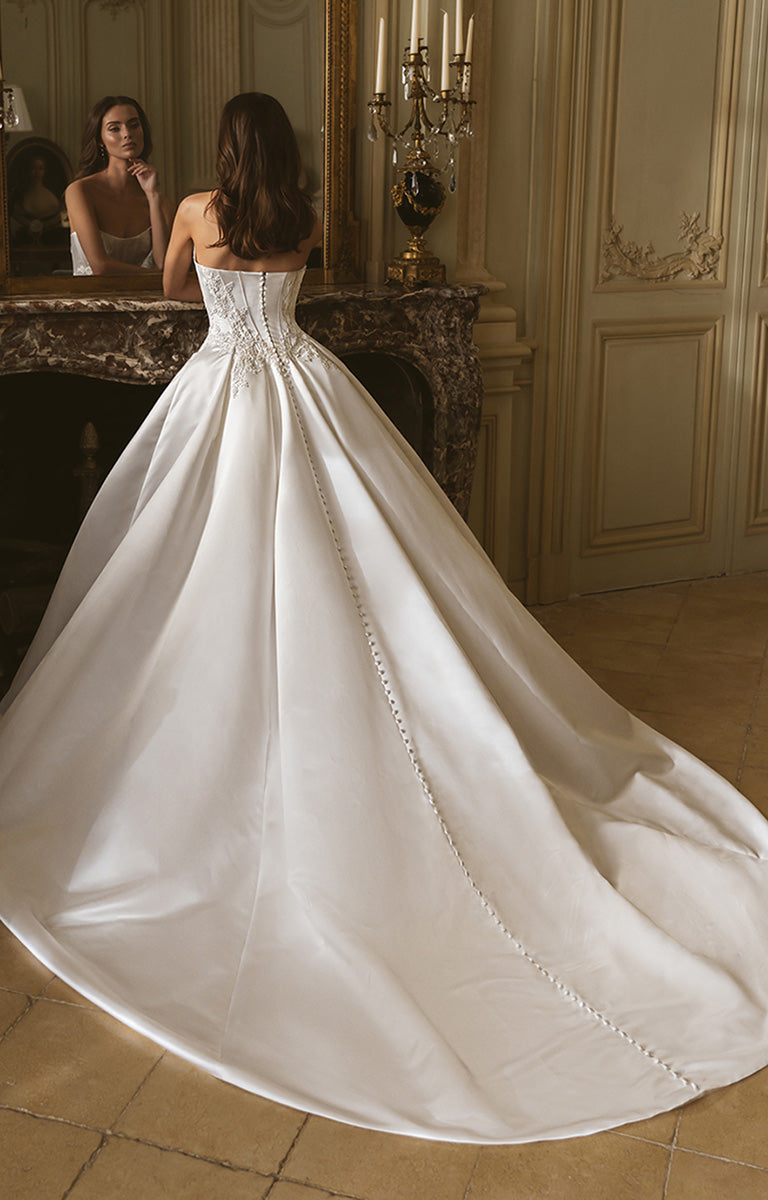 Woman in a white wedding dress standing in an elegant room with decorative walls.