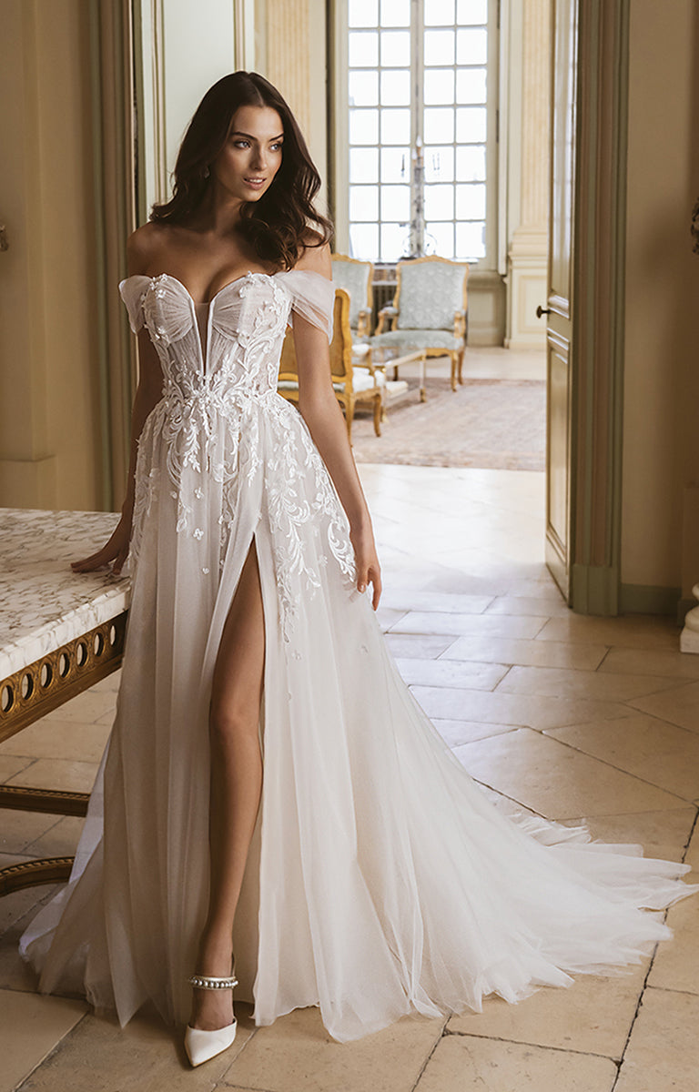 Woman in a white lace wedding dress with a high slit in an elegant room.