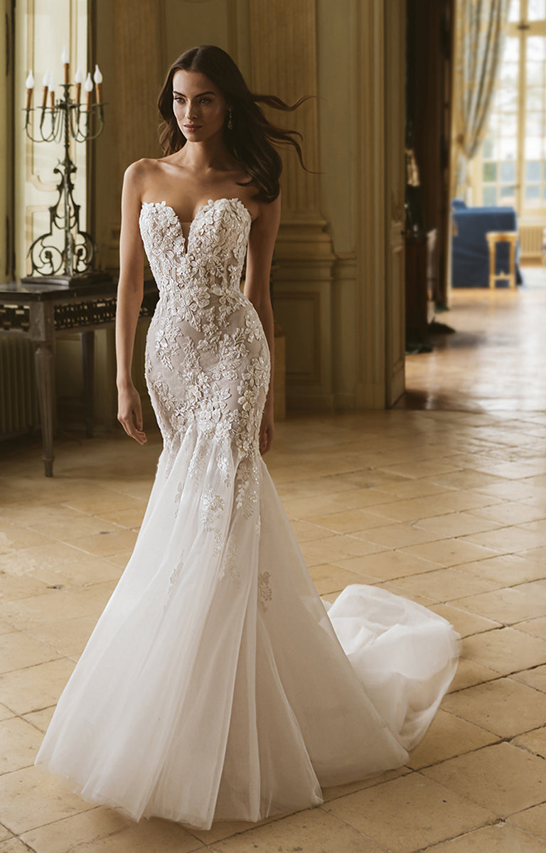 Woman wearing a strapless lace wedding dress in an elegant indoor setting.