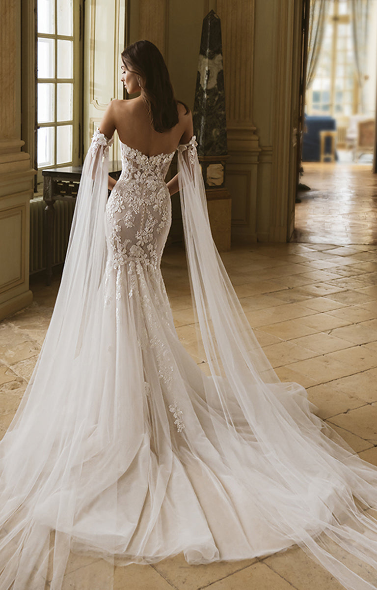 Woman in a white lace wedding dress with a long train in an elegant room.