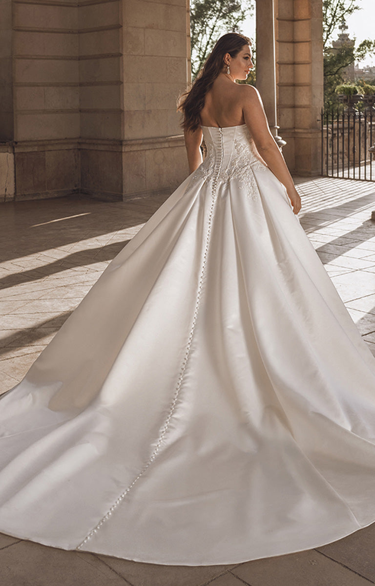 Woman in a white wedding dress standing in front of a classical building.