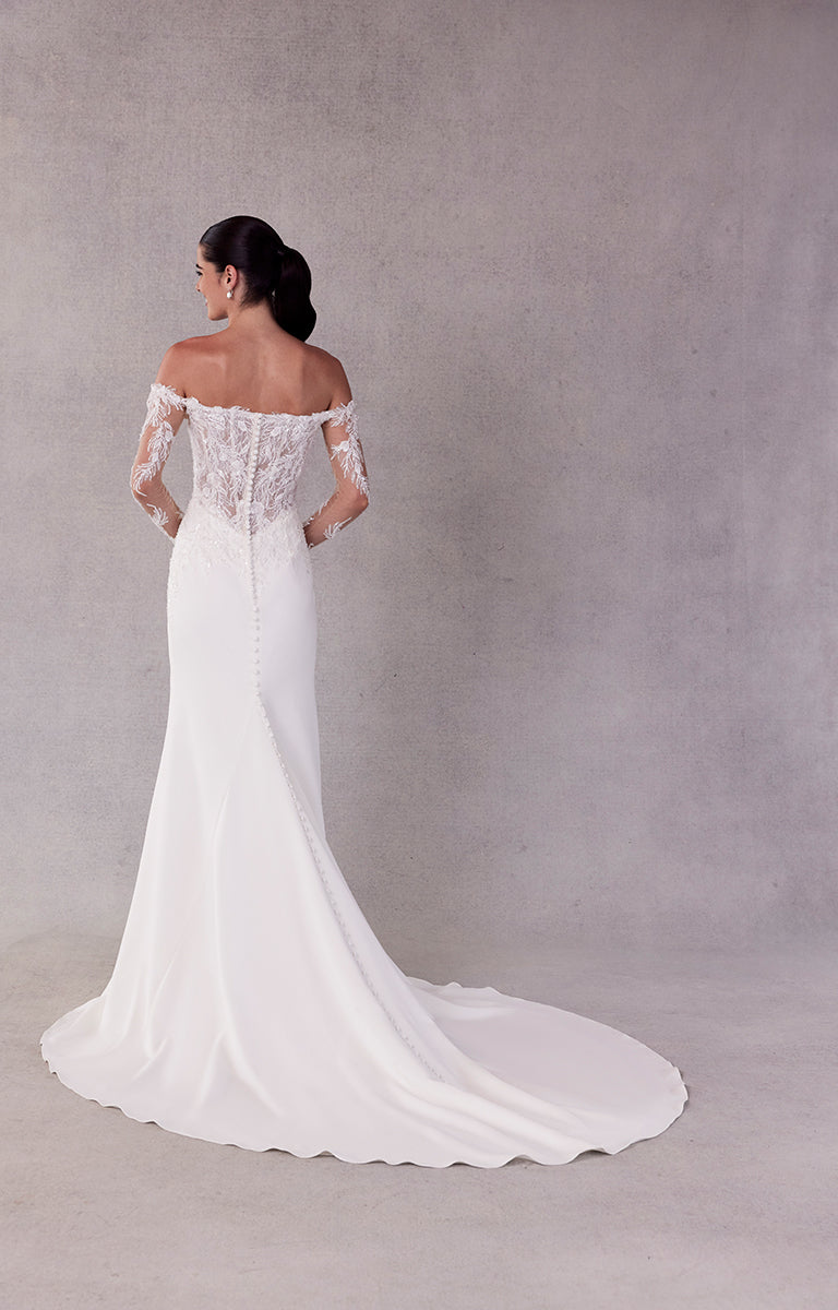 Woman wearing a white off-shoulder wedding dress with lace details on a gray background