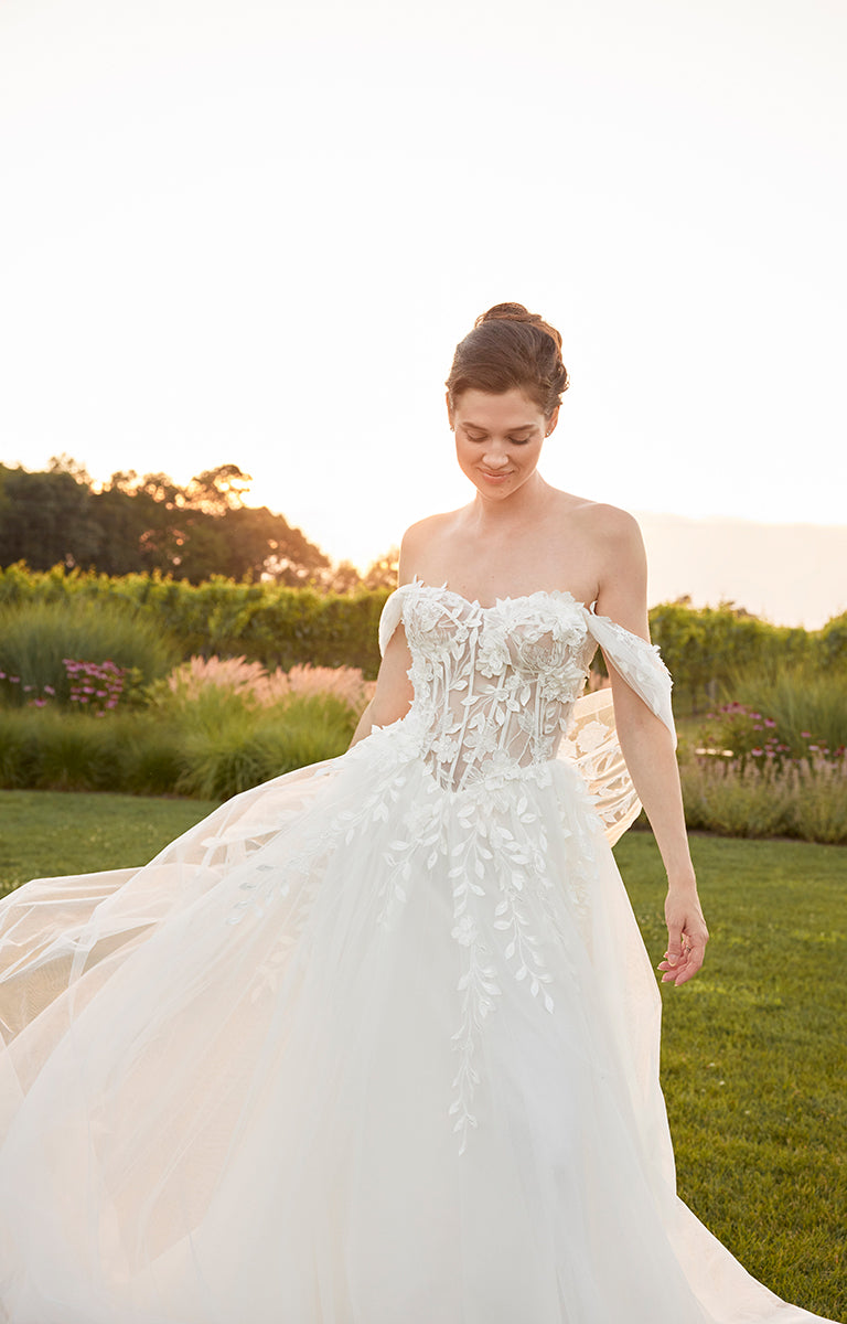 Woman in a white wedding dress standing in a garden with a sunset background