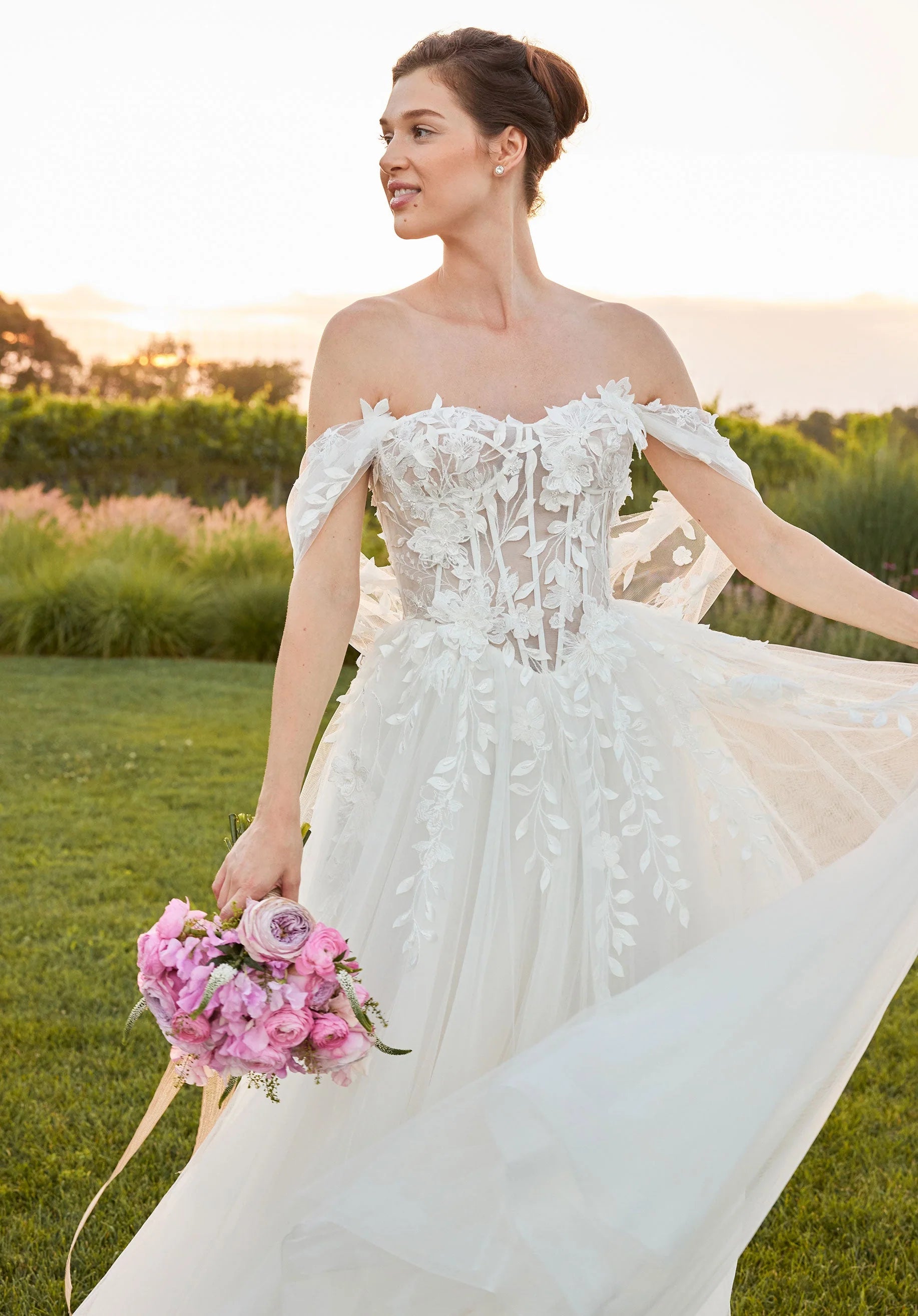Woman in a white wedding dress holding a bouquet of flowers outdoors.