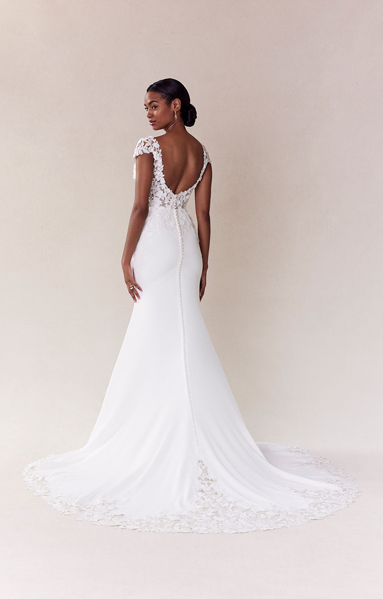 White wedding dress with lace details on a plain background