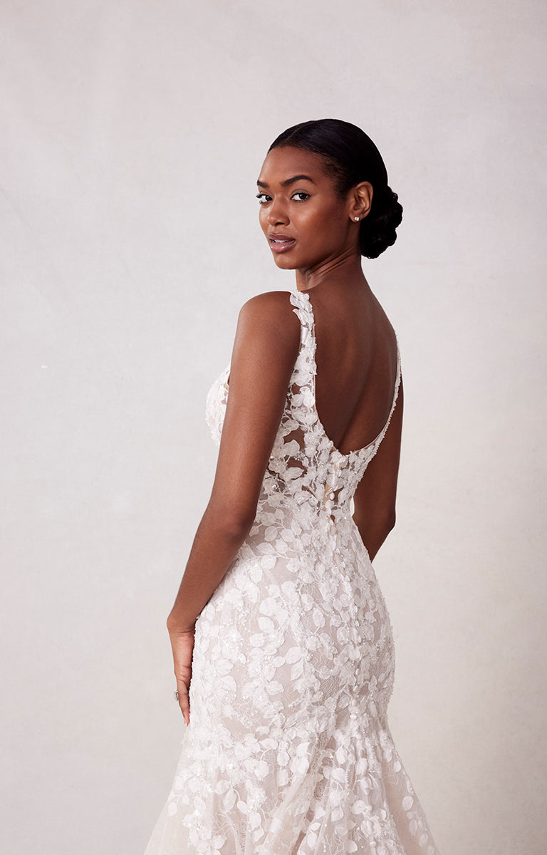 Woman wearing a white lace wedding dress with a plain background