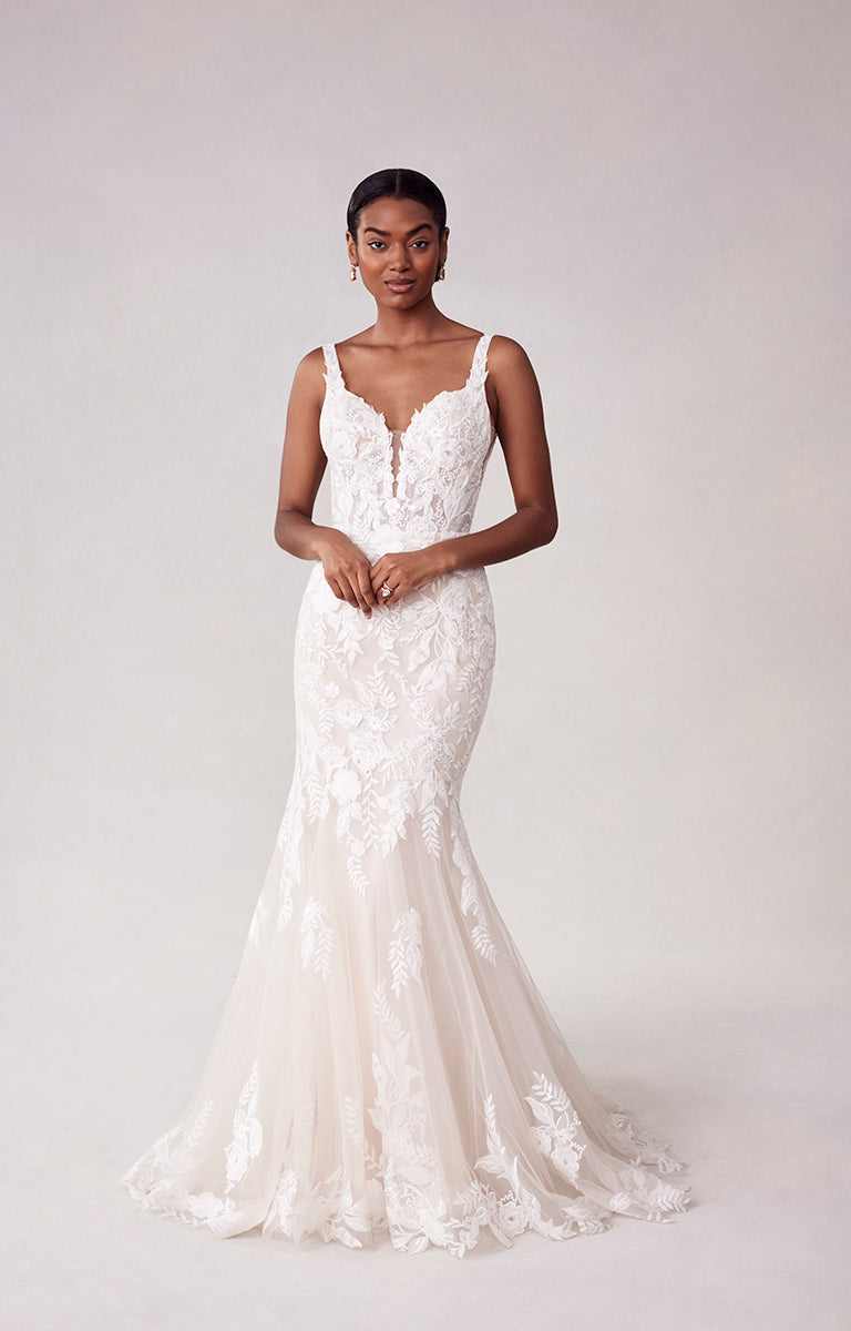 Woman wearing a white lace wedding dress against a plain background