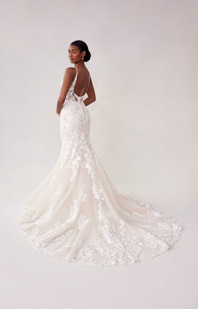 Woman wearing a white lace wedding dress on a plain background