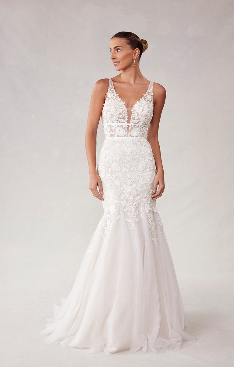 Woman wearing a white lace wedding dress on a plain background