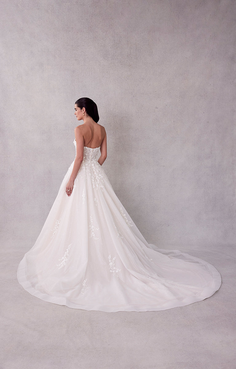White wedding dress with a long train on a plain background