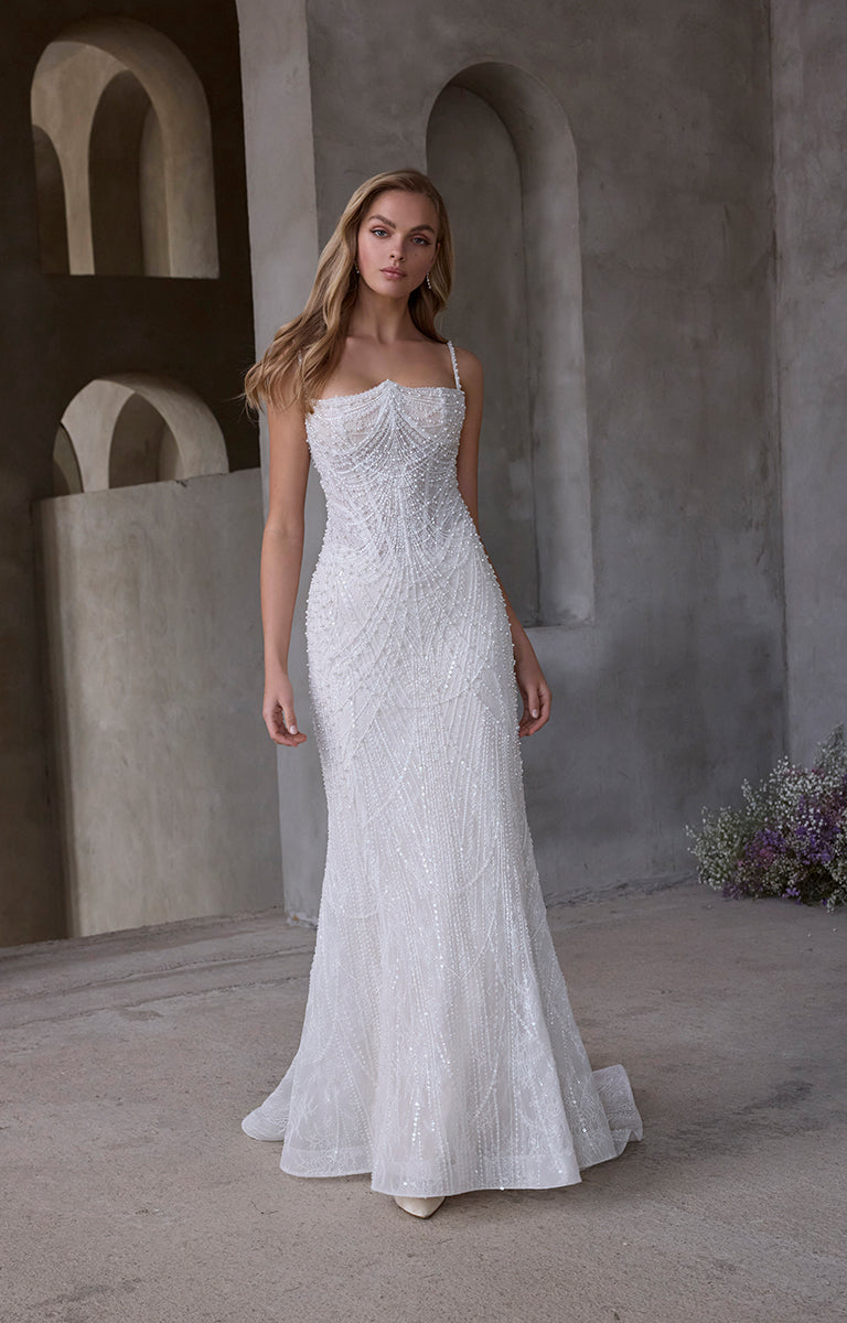 Woman in a strapless lace wedding dress standing in a rustic setting with stone arches.