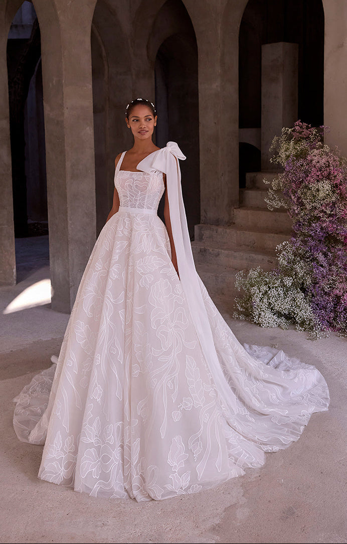 Woman in a white wedding dress standing in an archway with floral decorations.