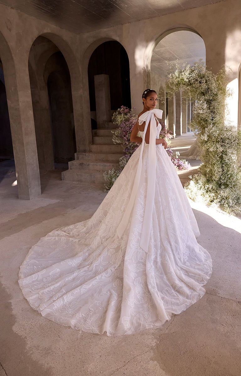 Woman in a white wedding dress with a long train in an elegant indoor setting.