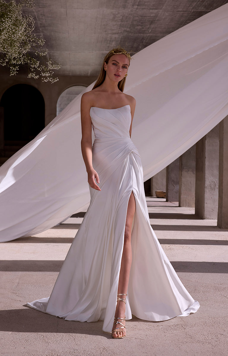 Woman in a strapless white gown with a high slit standing in an architectural setting.