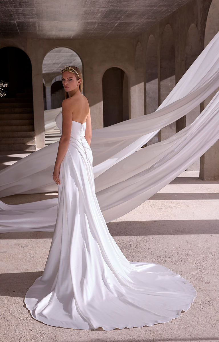 Woman in a white wedding dress with flowing train in an architectural setting
