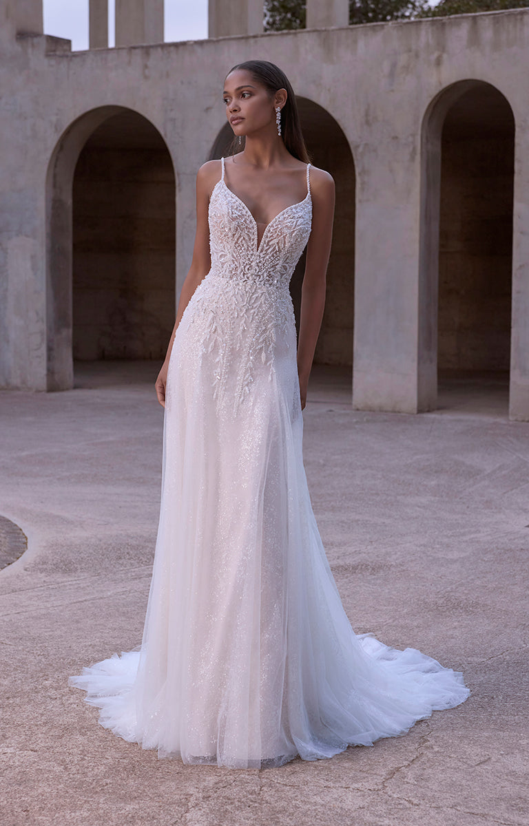 Woman in a white wedding dress standing in an outdoor setting with arches.