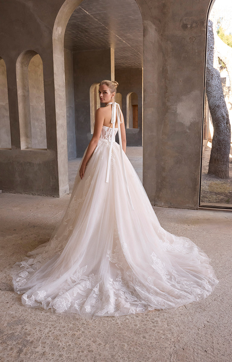 Woman in a white wedding dress standing in an architectural setting with arches.