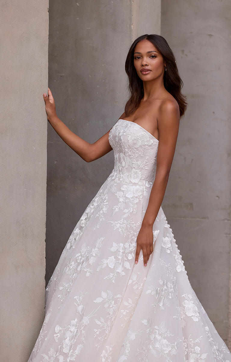 Woman wearing a strapless white wedding dress against a neutral background