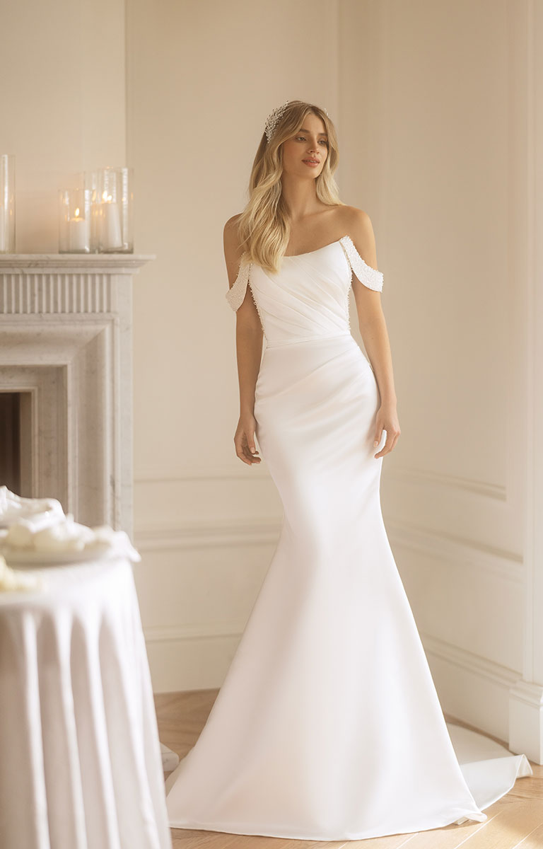Woman wearing a white off-shoulder wedding dress in a elegant room.