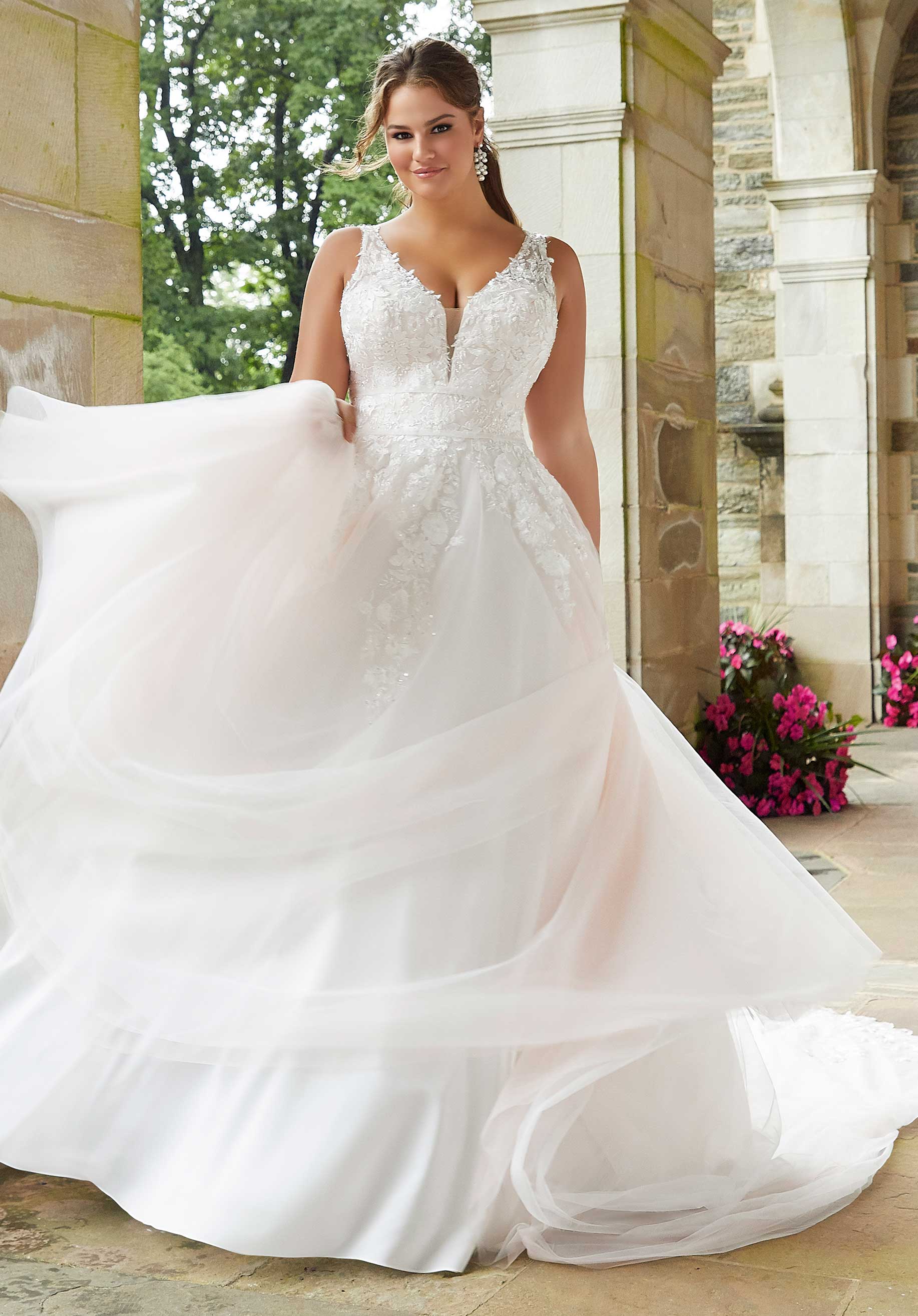 Woman in a white wedding dress standing outdoors with floral decorations.