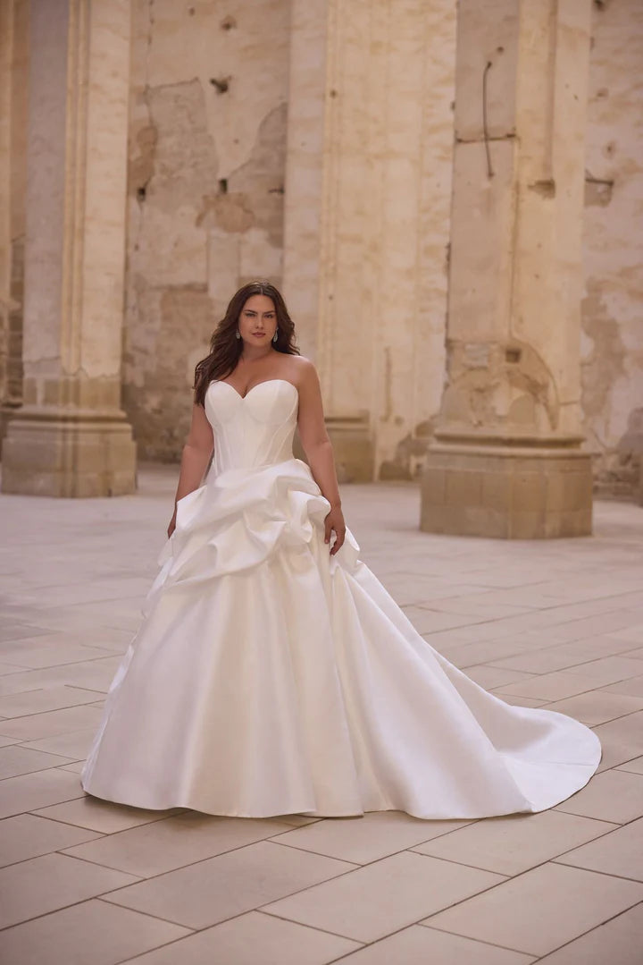 Woman in a white wedding dress standing in an outdoor setting with stone columns.