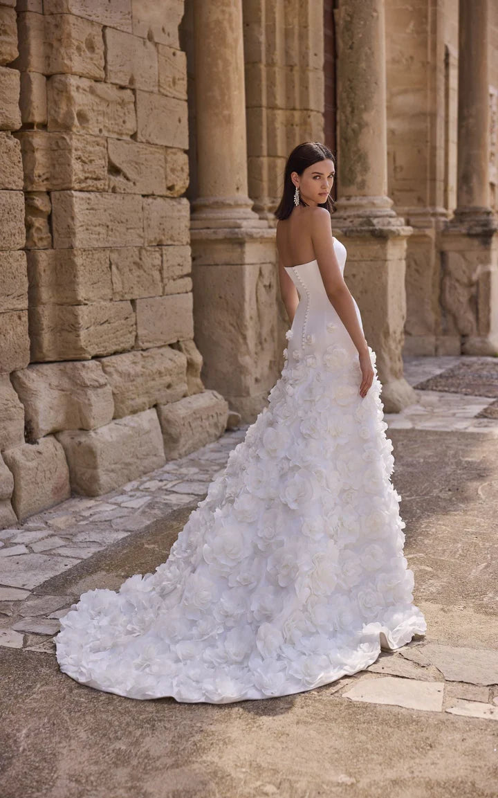 Woman in a white wedding dress standing in front of stone columns.