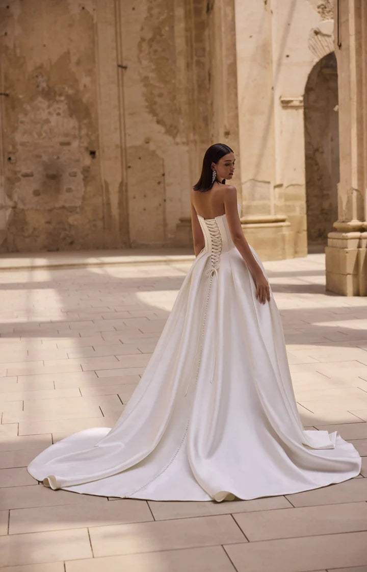 Woman in a white wedding dress standing in an ancient architectural setting