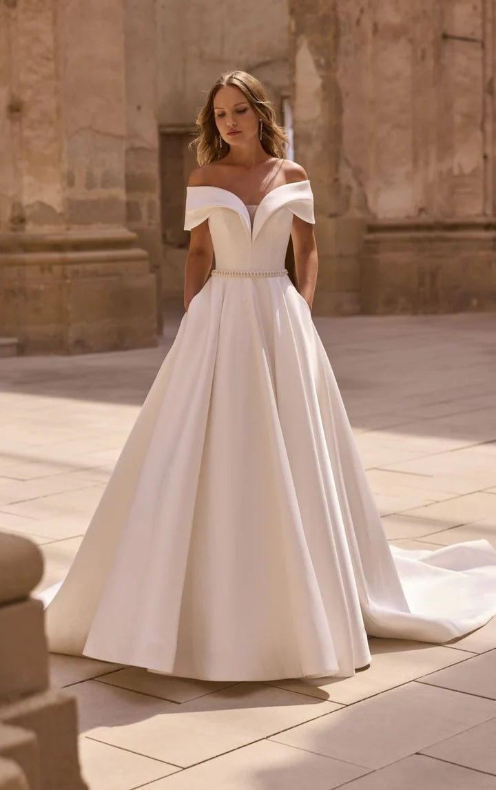 Woman in a white wedding dress standing in an outdoor setting with architectural background