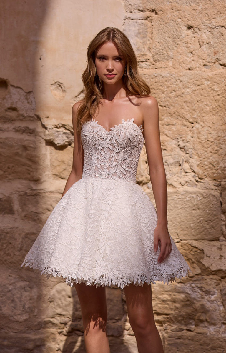 Woman wearing a white lace dress against a stone wall.