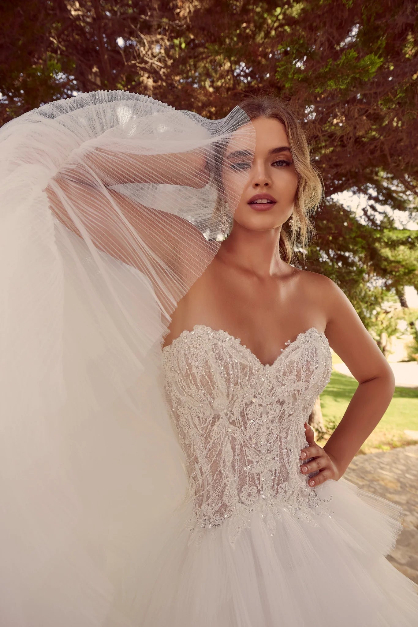 Woman in Zerlina A 69928A by Veni Infantino - Beaded Tulle A-Line Ball Gown with Convertible Neckline with a veil outdoors