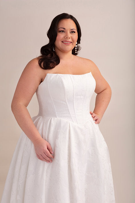 Woman wearing a white strapless dress against a plain background