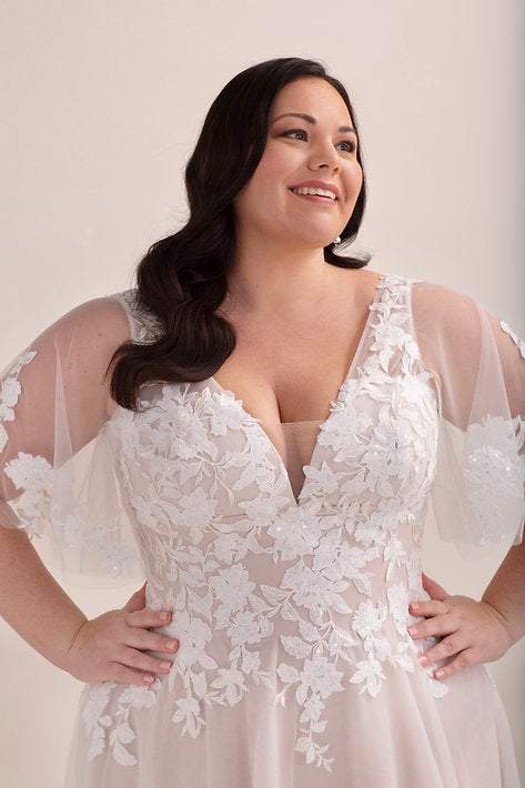 Woman wearing a white lace wedding dress against a plain background