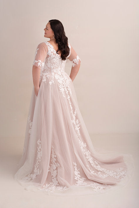 Woman wearing a white lace wedding dress against a plain background