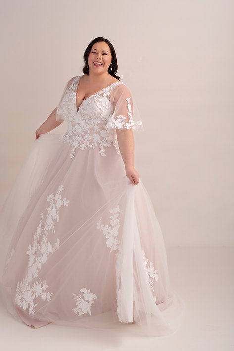 Woman wearing a white lace wedding dress on a plain background