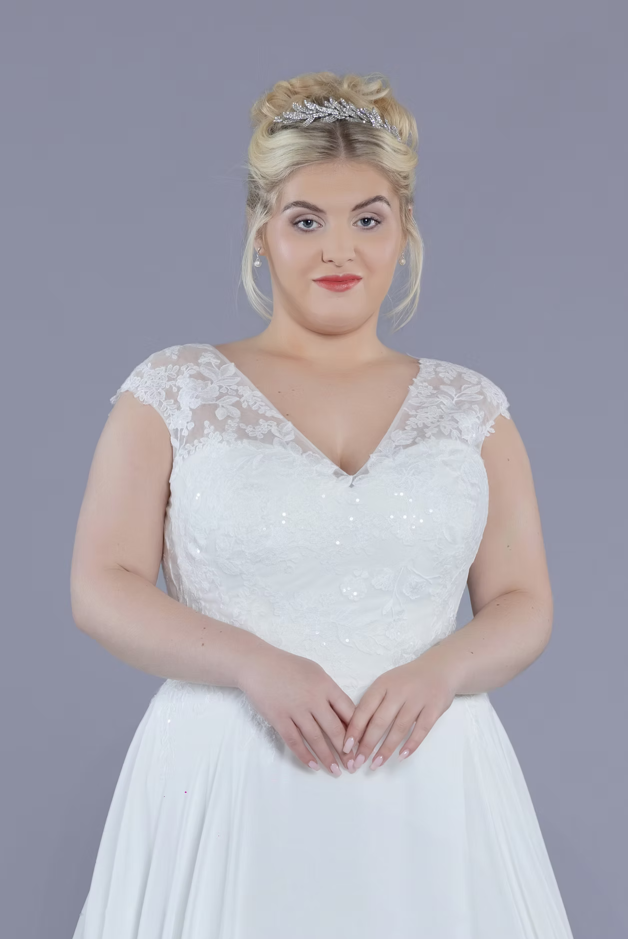 Woman wearing a white lace dress against a gray background