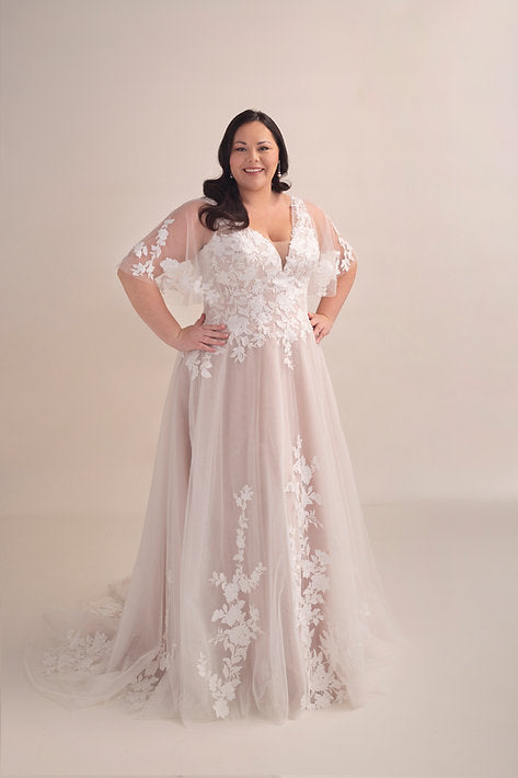 Woman wearing a floral lace wedding dress on a plain background