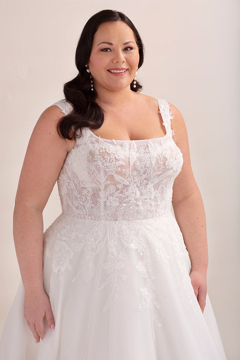 Woman wearing a white lace wedding dress against a plain background